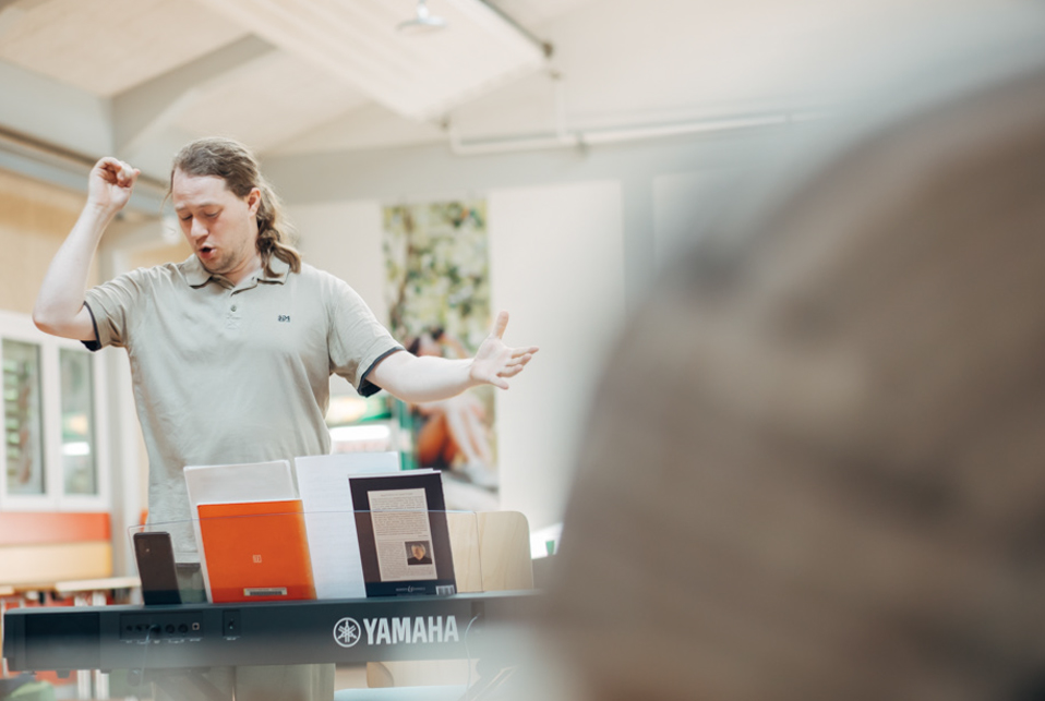 Ein Dirigent in Aktion. Einen Arm hält er gehoben, der andere weist nach vorn. Sein Gesicht verrät höchste Konzentration.